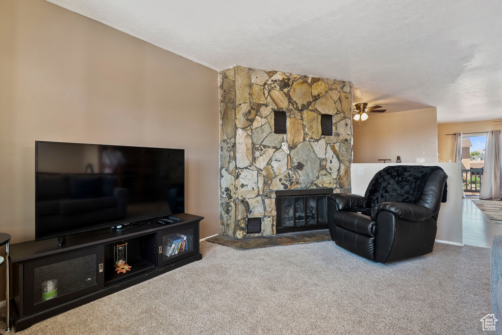Living room featuring carpet floors, a fireplace, and a ceiling fan