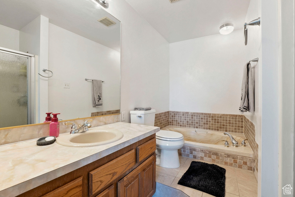 Full bath featuring tile patterned floors, vanity, a garden tub, toilet, and a shower stall