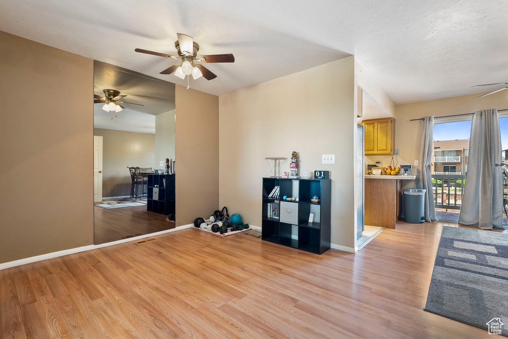 Unfurnished living room with ceiling fan, light wood-style flooring, and baseboards