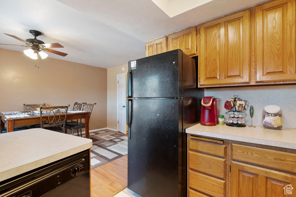 Kitchen featuring black appliances, light countertops, baseboards, ceiling fan, and light wood-style flooring