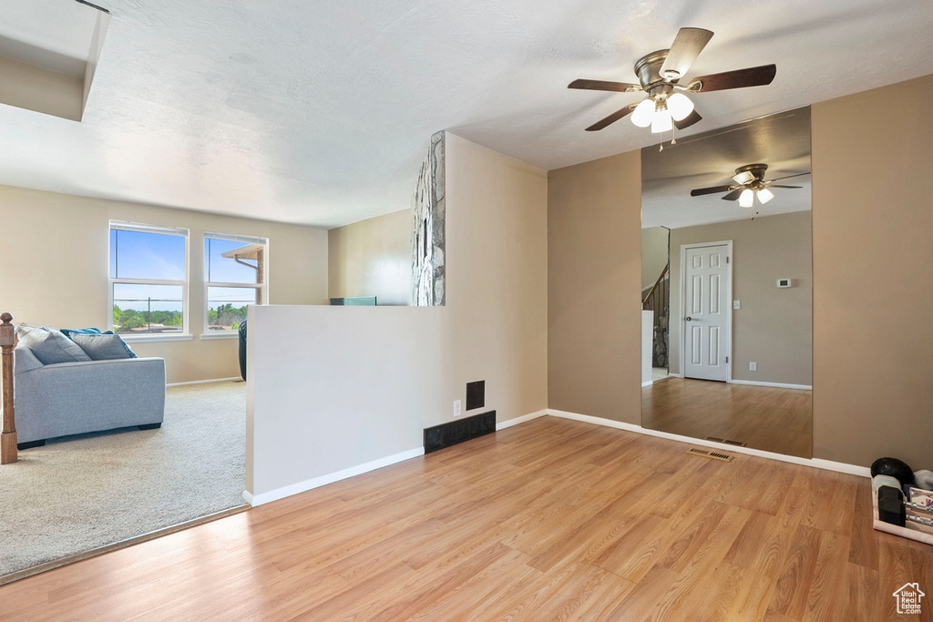 Unfurnished living room with a ceiling fan, baseboards, wood finished floors, and stairway
