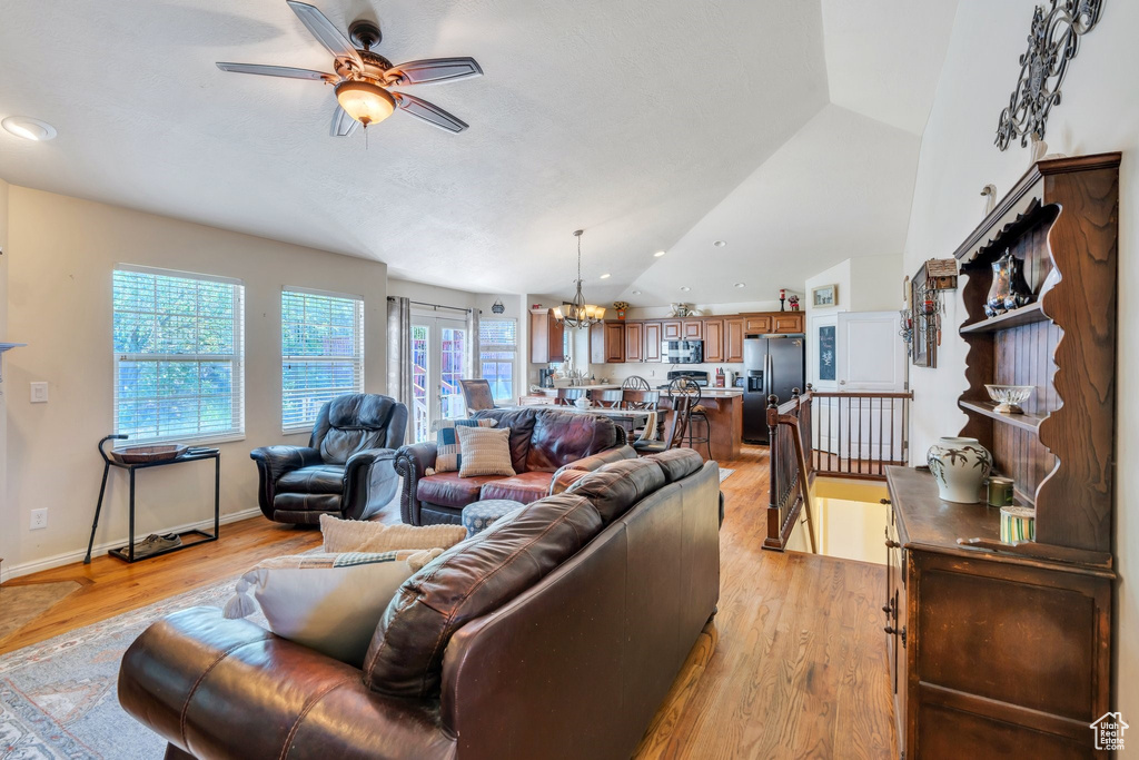 Living room featuring a ceiling fan, a chandelier, vaulted ceiling, light wood finished floors, and recessed lighting