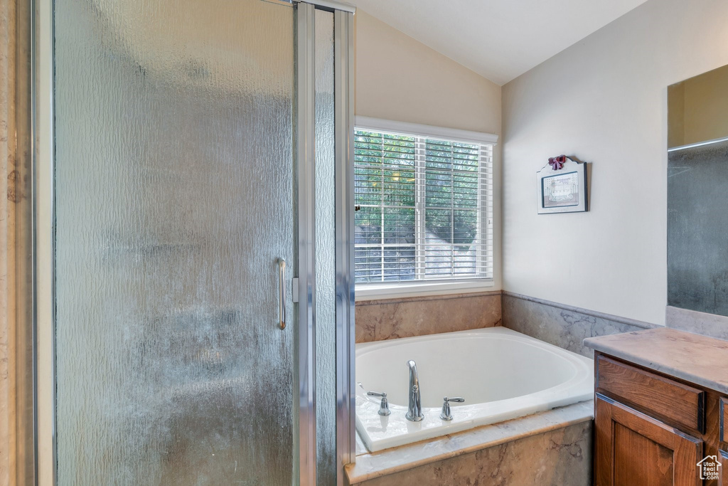 Full bath with a stall shower, a bath, lofted ceiling, and vanity