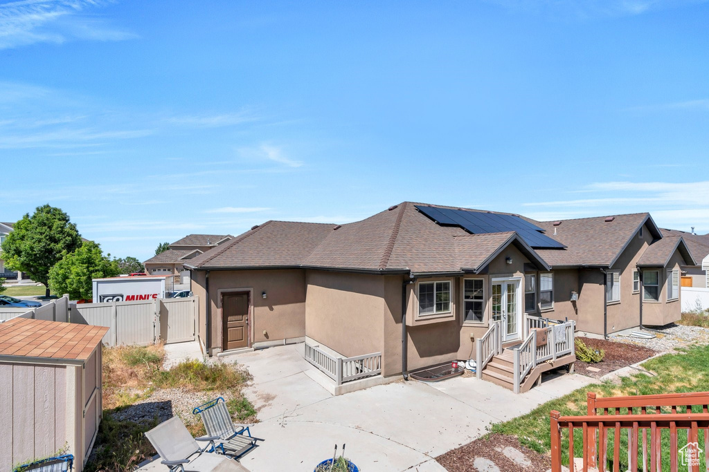 View of front of property featuring a patio area, stucco siding, a deck, roof with shingles, and a gate