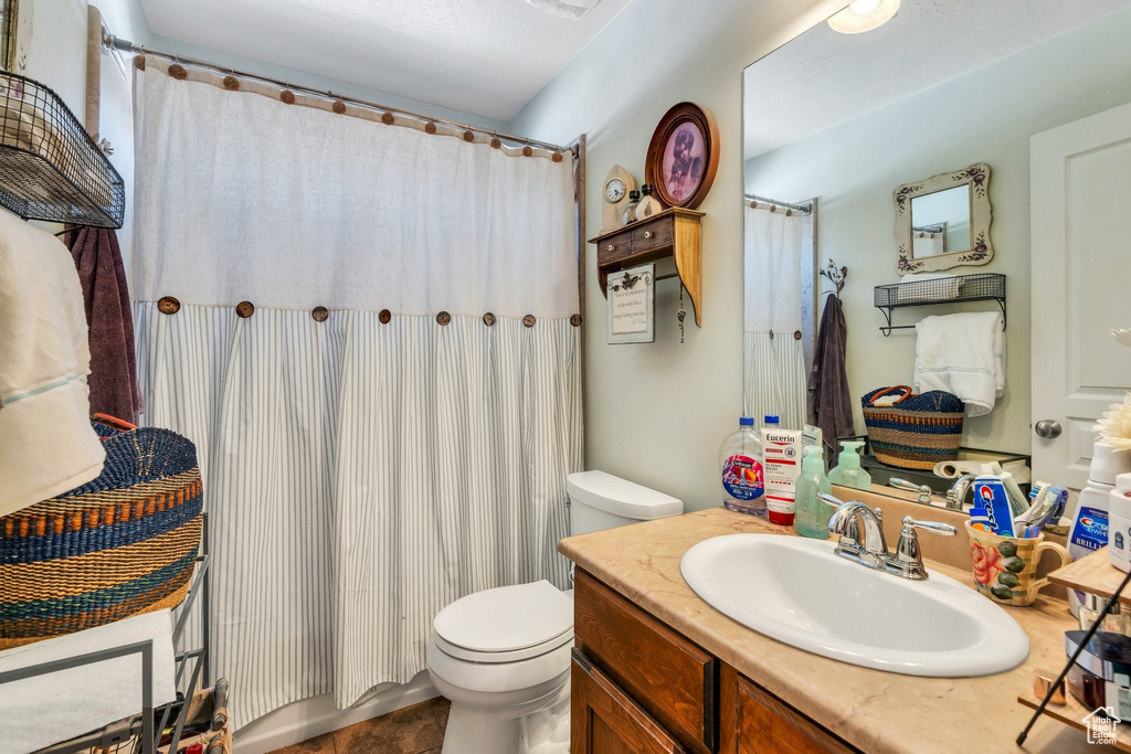 Bathroom with toilet, vanity, and a shower with shower curtain