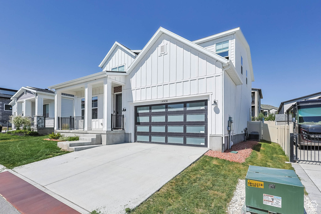 Modern farmhouse featuring board and batten siding, a garage, covered porch, and concrete driveway