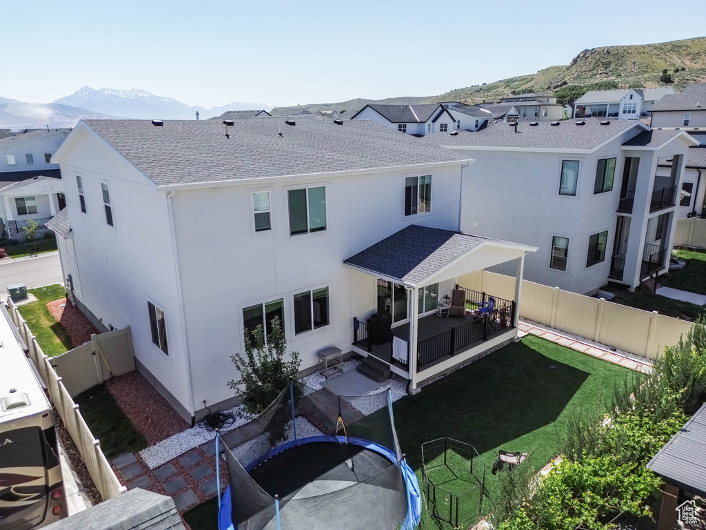 Rear view of house with a mountain view, roof with shingles, a patio area, a residential view, and stucco siding