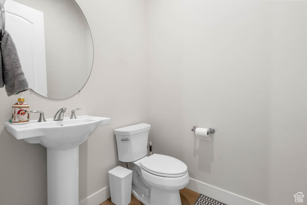 Bathroom with toilet, baseboards, wood finished floors, and a sink