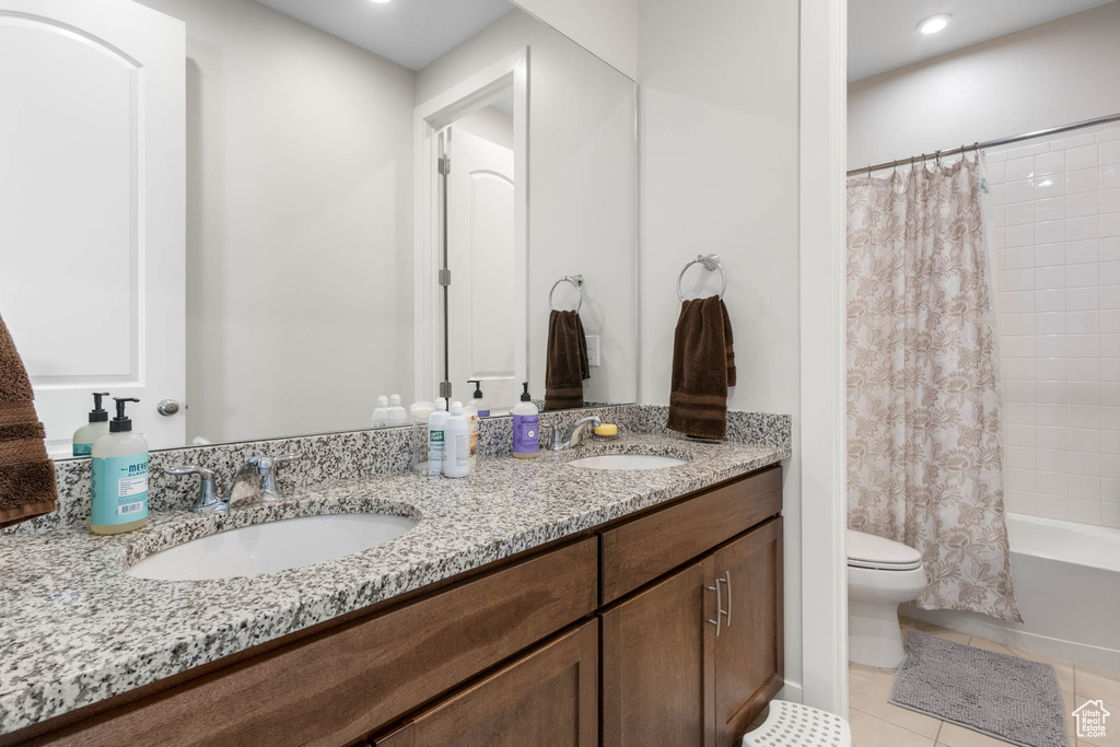 Bathroom featuring double vanity, toilet, shower / bath combo with shower curtain, tile patterned flooring, and recessed lighting