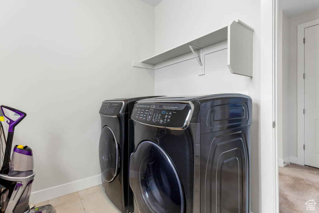 Laundry room featuring washer and clothes dryer, baseboards, and light tile patterned floors