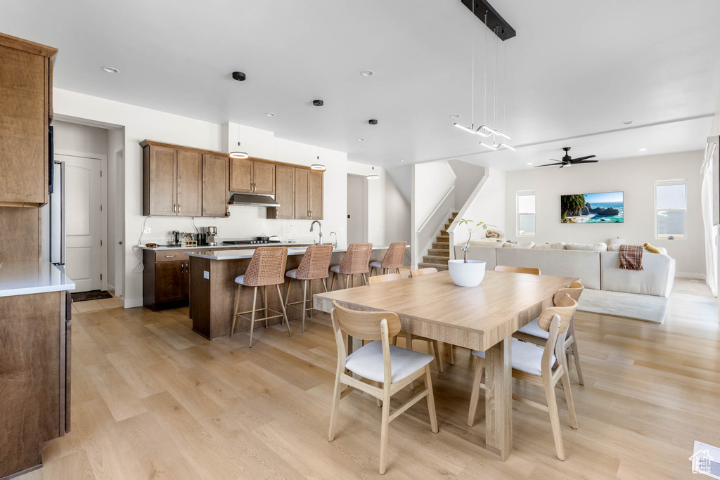Dining area with stairway, light wood-type flooring, and a ceiling fan