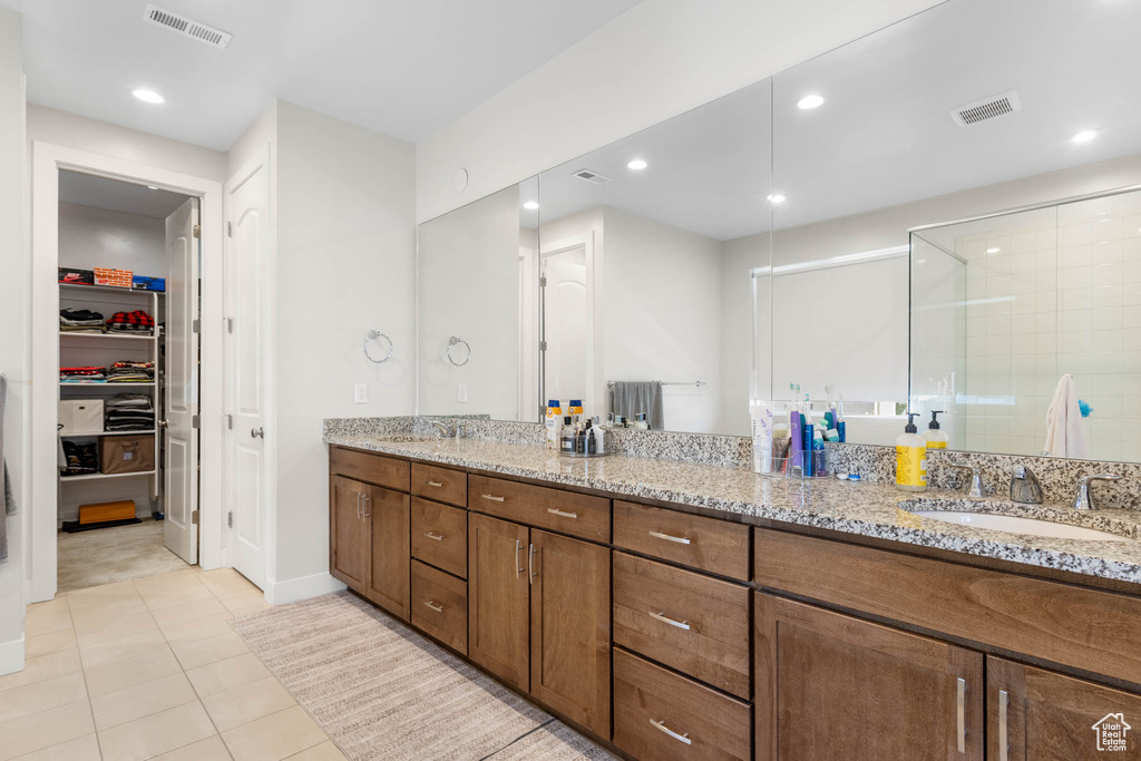 Full bath with double vanity, a stall shower, tile patterned floors, recessed lighting, and a walk in closet