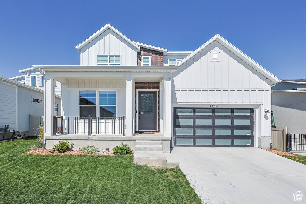 Modern farmhouse featuring board and batten siding, a porch, concrete driveway, an attached garage, and a front lawn