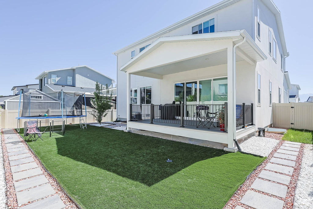 Back of property featuring a trampoline and stucco siding