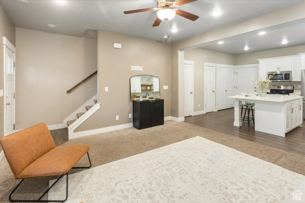 Living room featuring carpet, ceiling fan, baseboards, stairway, and recessed lighting