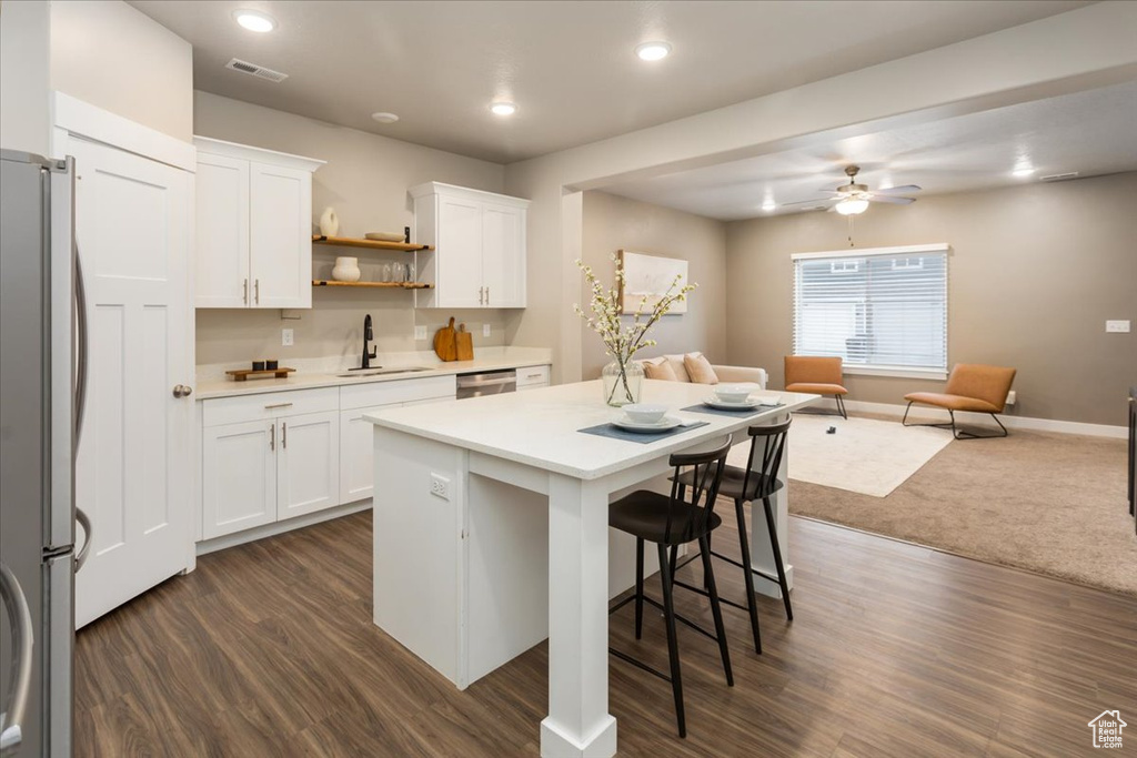 Kitchen featuring a sink, stainless steel appliances, open floor plan, a kitchen island, and light countertops