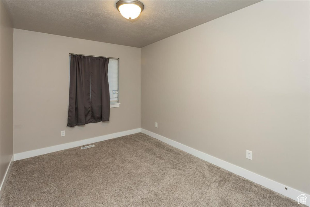 Unfurnished room featuring a textured ceiling, carpet floors, and baseboards
