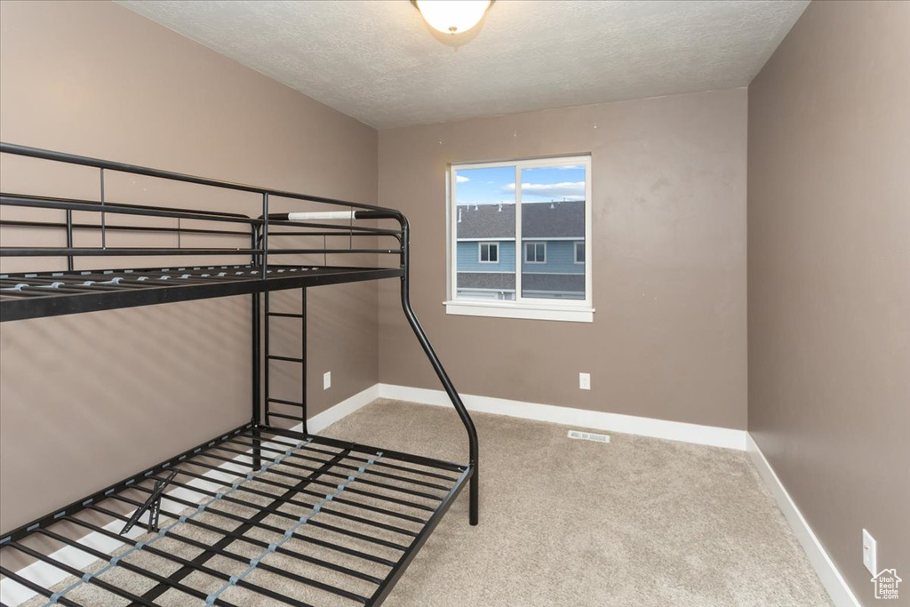 Unfurnished bedroom with carpet floors, baseboards, and a textured ceiling