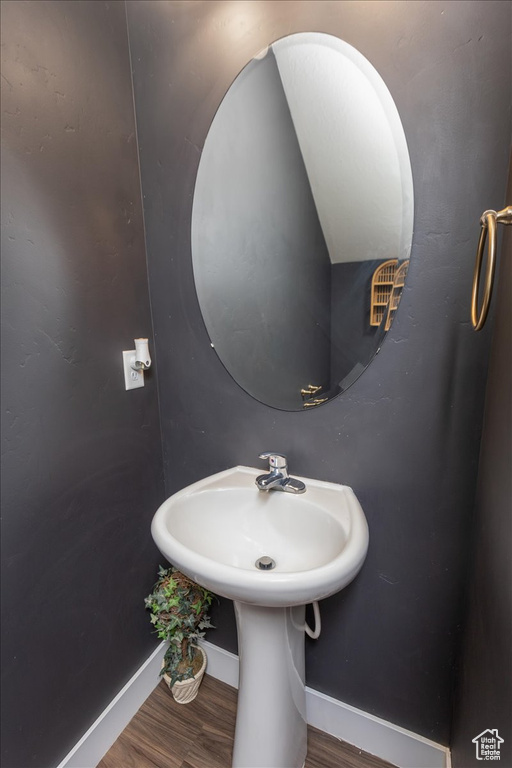 Bathroom with baseboards, wood finished floors, and a sink