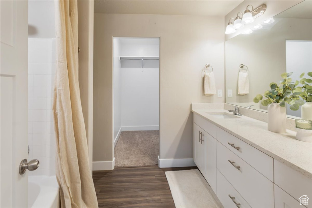 Bathroom featuring vanity, wood finished floors, shower / tub combo, and baseboards