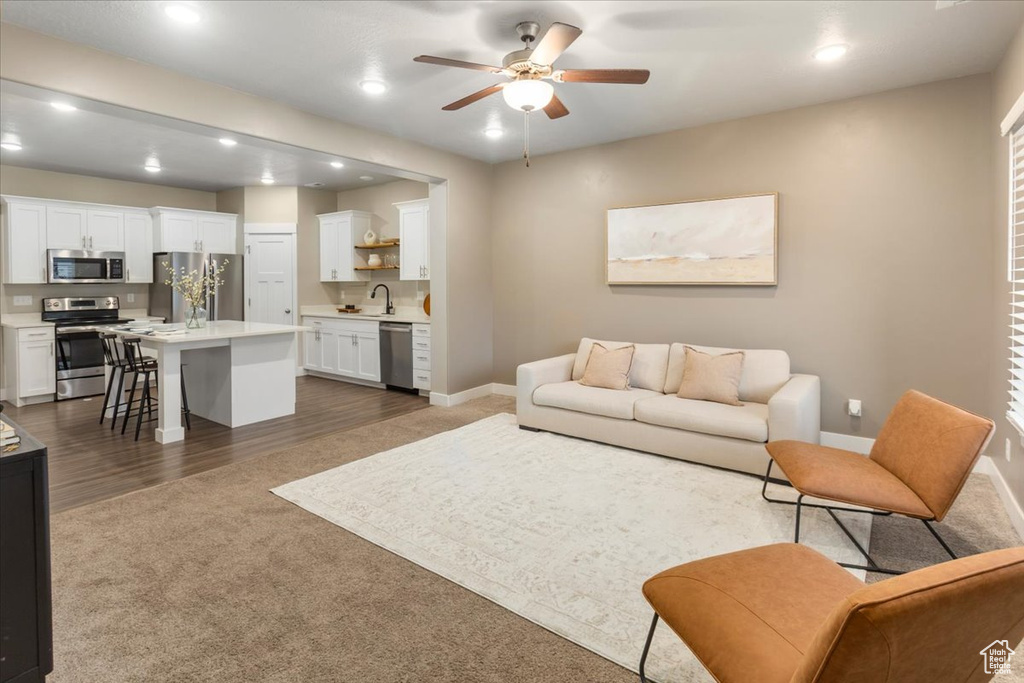 Living area with a ceiling fan, recessed lighting, dark carpet, and baseboards