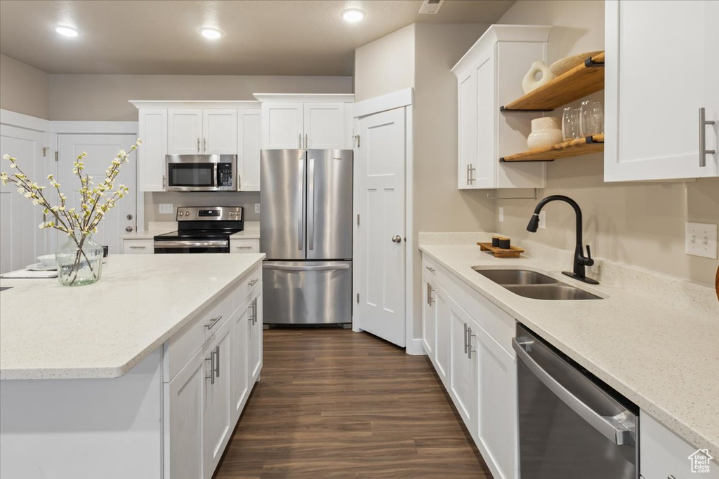 Kitchen with appliances with stainless steel finishes, a sink, open shelves, white cabinets, and recessed lighting
