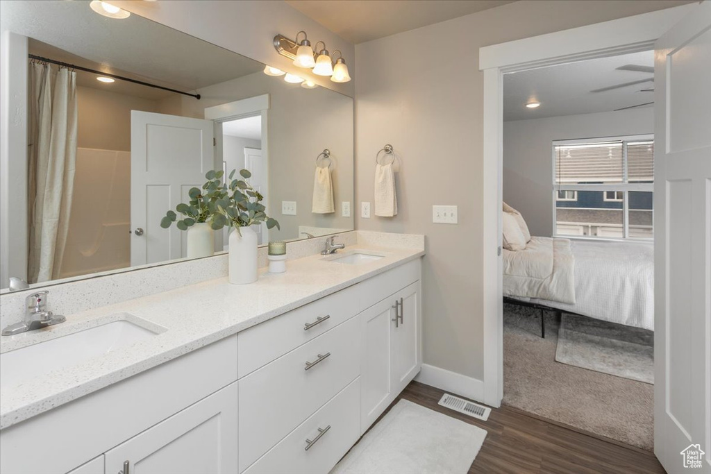Ensuite bathroom with wood finished floors, double vanity, baseboards, and curtained shower