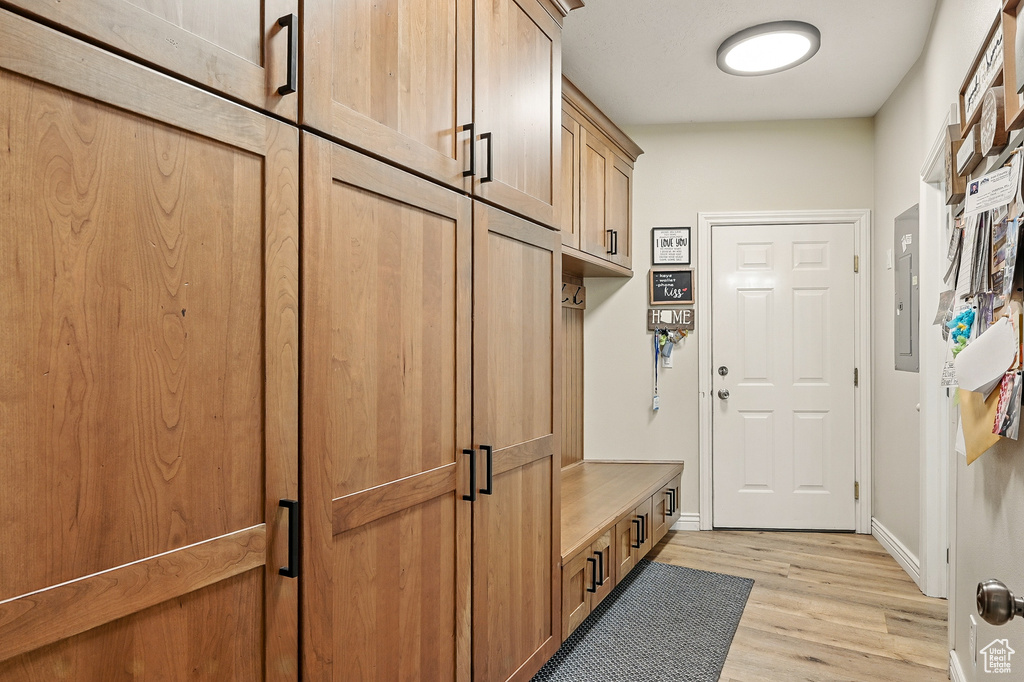 Mudroom with light wood-style floors, baseboards, and electric panel