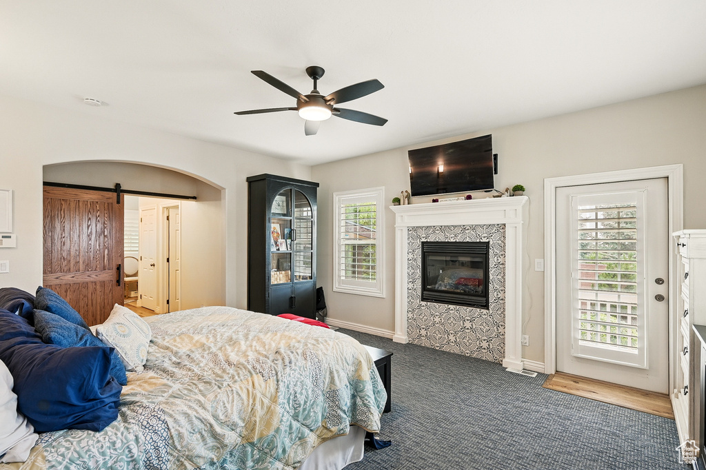 Bedroom featuring a barn door, carpet, a tile fireplace, access to exterior, and baseboards