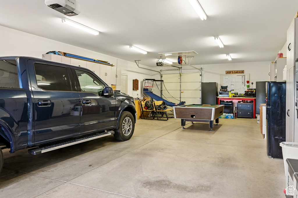Garage featuring freestanding refrigerator and a garage door opener
