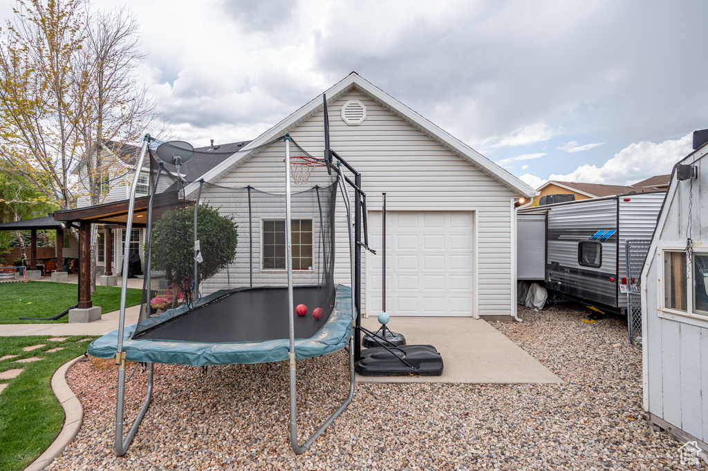 Back of property featuring a trampoline, a garage, and a patio