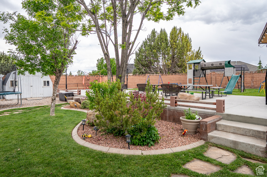 View of yard featuring a trampoline, a playground, and a patio