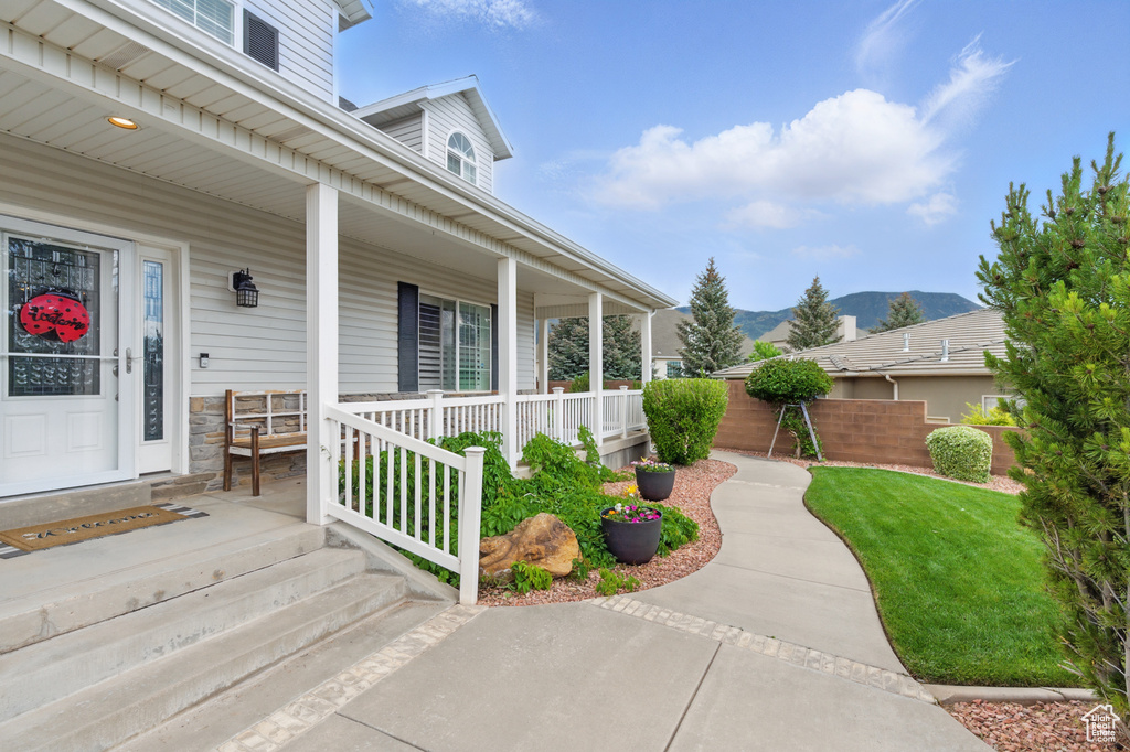 Doorway to property featuring a porch, a mountain view, and a yard