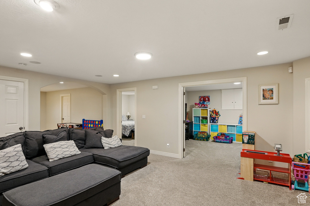 Carpeted living area featuring arched walkways, recessed lighting, and baseboards