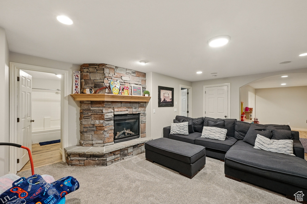 Living area with a stone fireplace, arched walkways, and recessed lighting