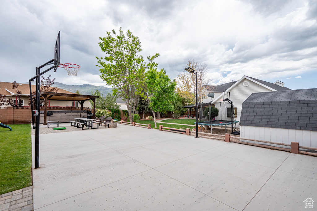 View of sport court featuring a trampoline, a shed, and a playground