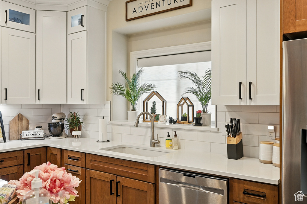 Kitchen featuring a sink, appliances with stainless steel finishes, brown cabinets, and decorative backsplash