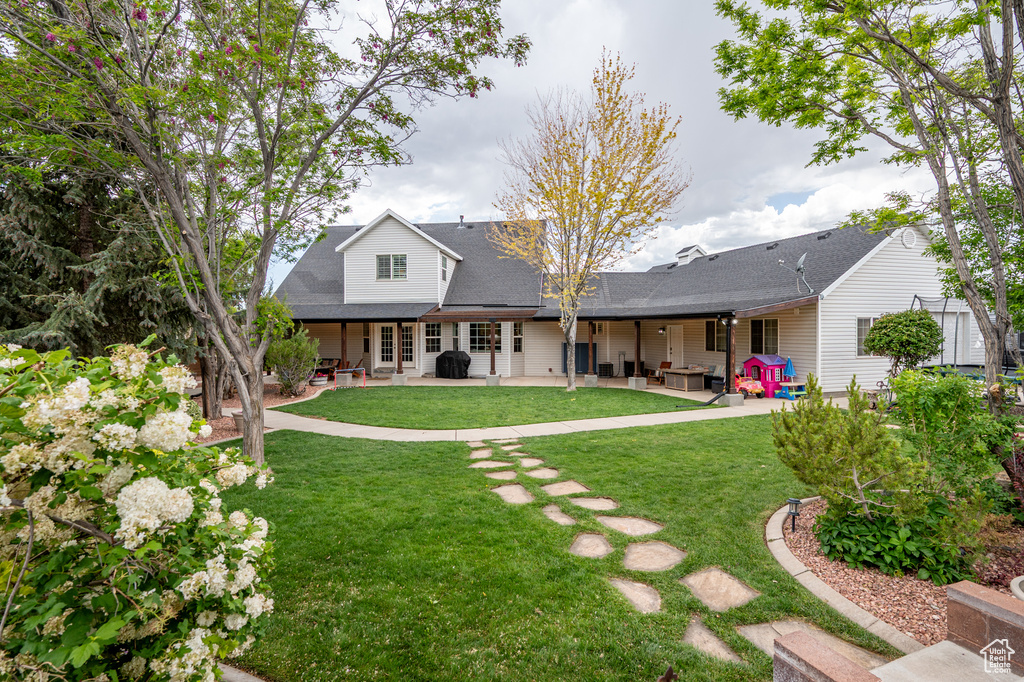 Back of property with a patio area, a lawn, and a shingled roof