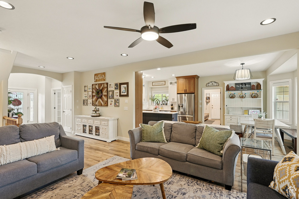 Living room with arched walkways, recessed lighting, a ceiling fan, light wood finished floors, and baseboards