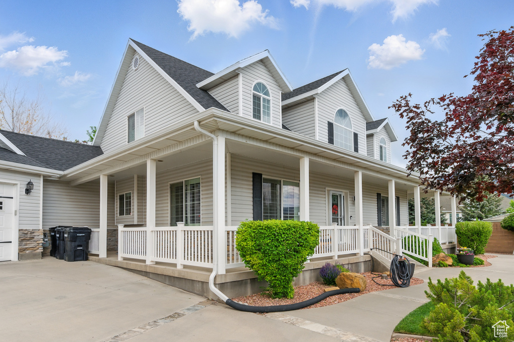 Farmhouse with covered porch, a shingled roof, and driveway