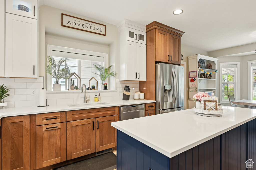 Kitchen featuring appliances with stainless steel finishes, a sink, brown cabinets, light countertops, and recessed lighting