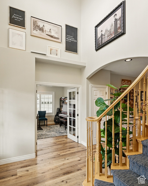 Foyer entrance featuring baseboards, wood finished floors, stairs, arched walkways, and a towering ceiling
