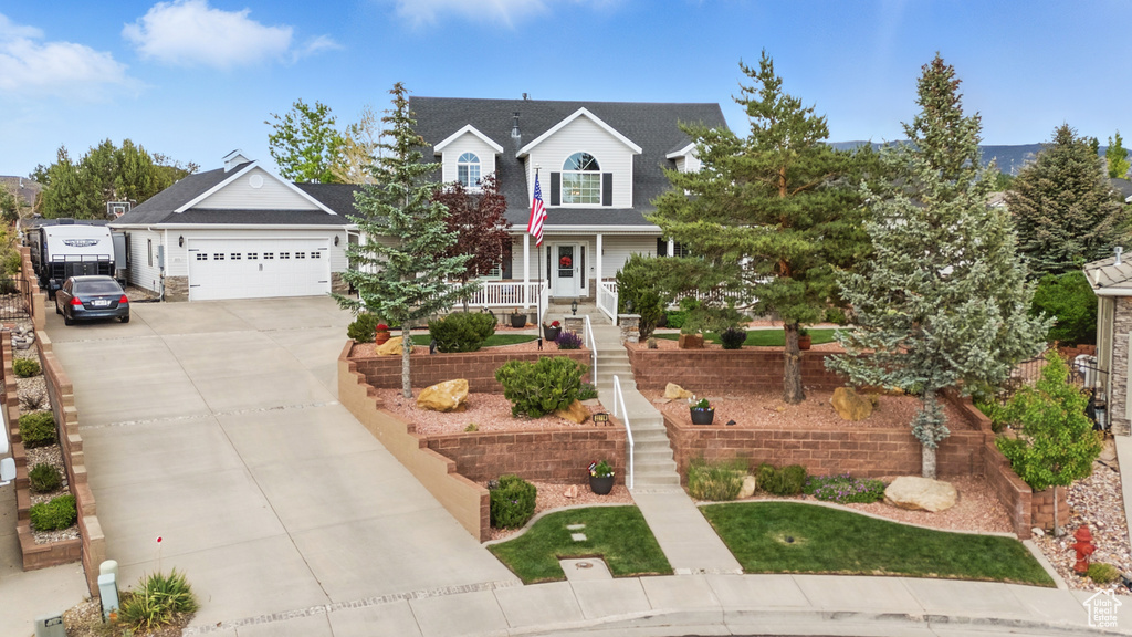 View of front facade featuring concrete driveway, a garage, and covered porch