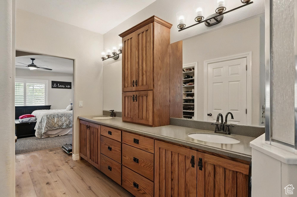 Bathroom featuring double vanity, ceiling fan, wood finished floors, and ensuite bathroom