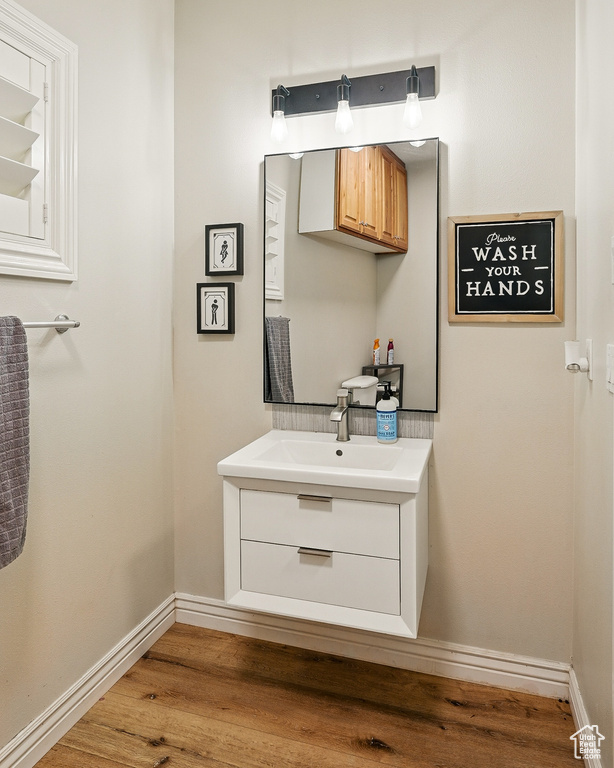 Bathroom with vanity, wood finished floors, and baseboards