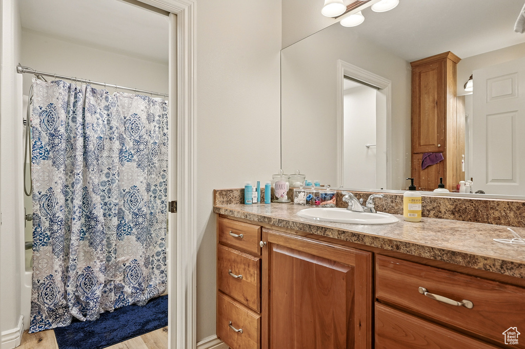 Bathroom with vanity, wood finished floors, and shower / tub combo with curtain