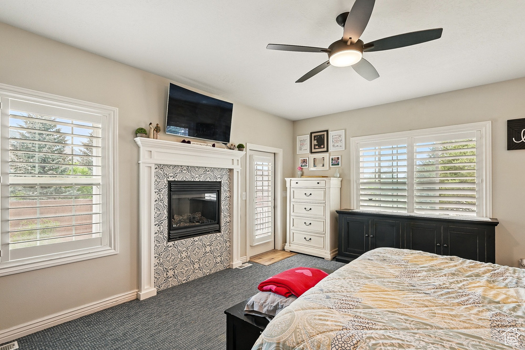 Bedroom featuring a tiled fireplace, carpet, ceiling fan, and access to exterior