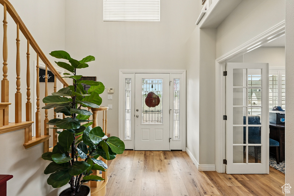 Foyer entrance featuring a high ceiling, stairs, hardwood / wood-style flooring, and baseboards