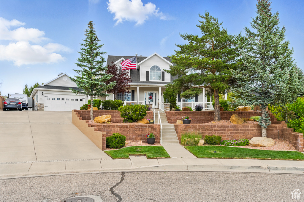 Traditional-style home with stairs, concrete driveway, a porch, and an attached garage
