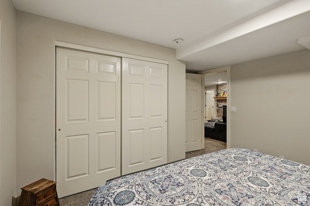 Bedroom featuring carpet floors, a stone fireplace, and a closet
